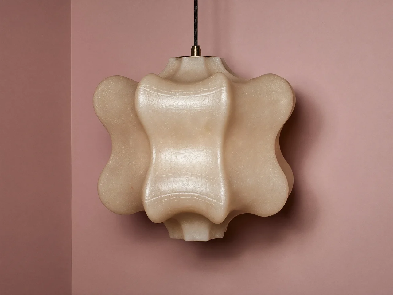 Skulpturale Pendelleuchte aus Opalglas vor einer pastellfarbenen Wand